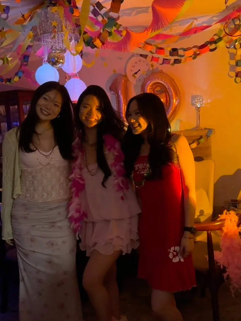 Amanda with two friends at a warmly lit birthday party