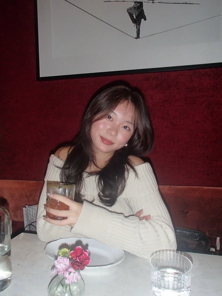 Amanda seated at dinner against a deep red wall