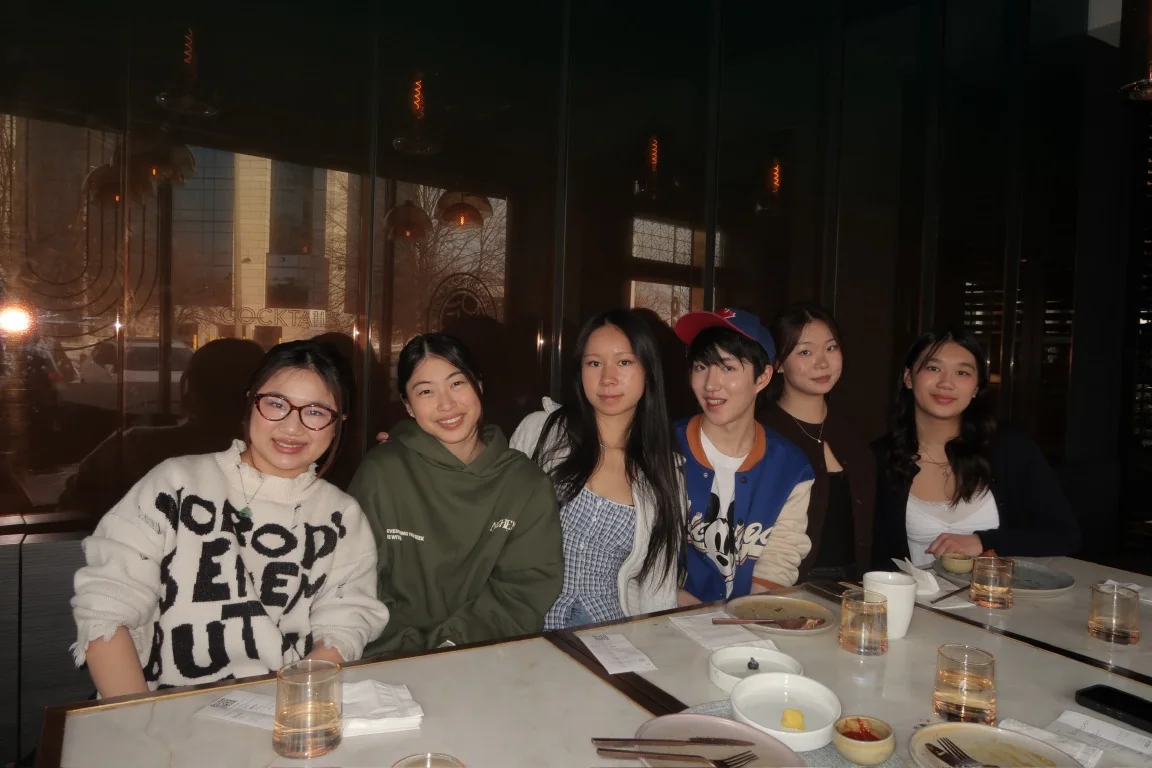 Six friends seated together around a restaurant table
