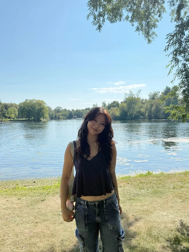 Amanda standing beside a sunlit lake on a clear summer day