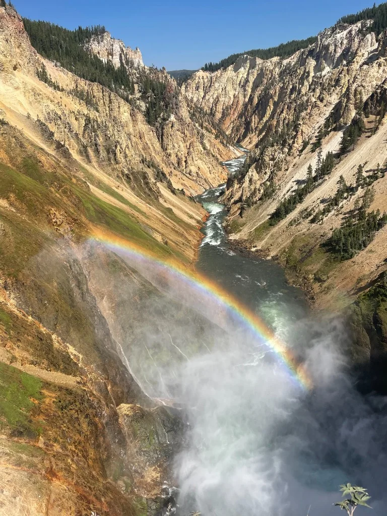 A rainbow crossing mist above a river in Yellowstone canyon